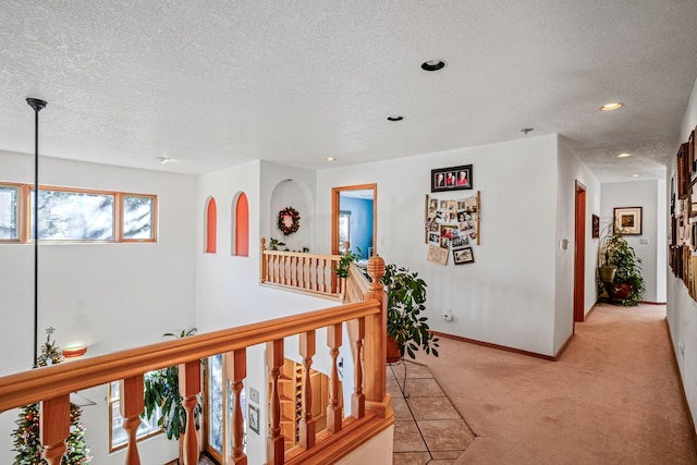 hallway featuring a textured ceiling and light carpet