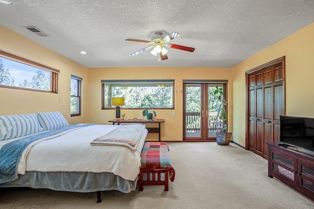 bedroom with ceiling fan, access to exterior, light carpet, and multiple windows