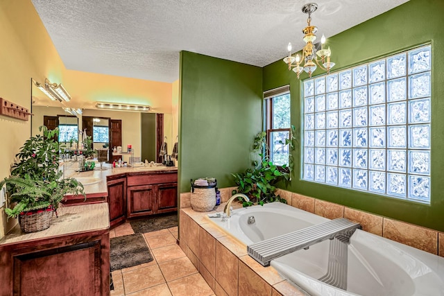 bathroom with tile patterned flooring, a textured ceiling, vanity, and a relaxing tiled tub