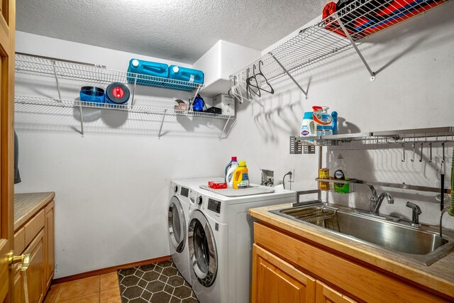 laundry room featuring cabinets, a textured ceiling, sink, washer and dryer, and light tile patterned floors