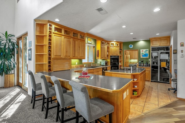 kitchen featuring a breakfast bar, a textured ceiling, sink, light hardwood / wood-style flooring, and a center island