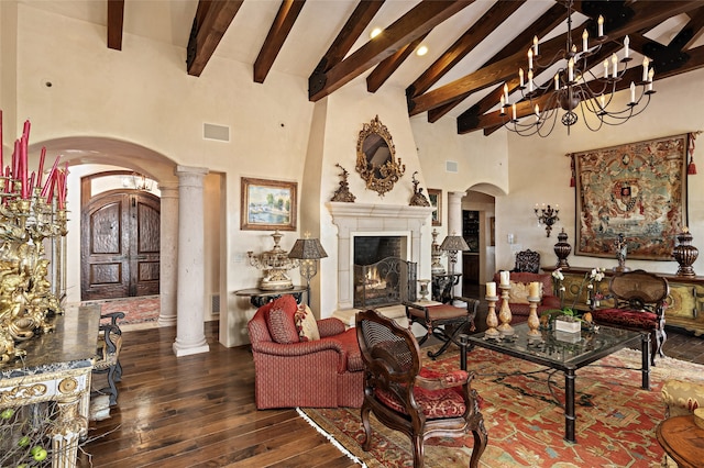 living room with a chandelier, decorative columns, high vaulted ceiling, and dark wood-type flooring