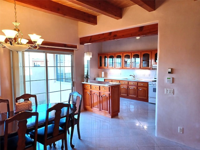 kitchen with brown cabinetry, glass insert cabinets, an inviting chandelier, light countertops, and a sink