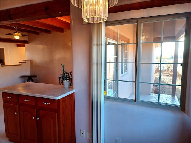 kitchen with light countertops, a notable chandelier, and beamed ceiling