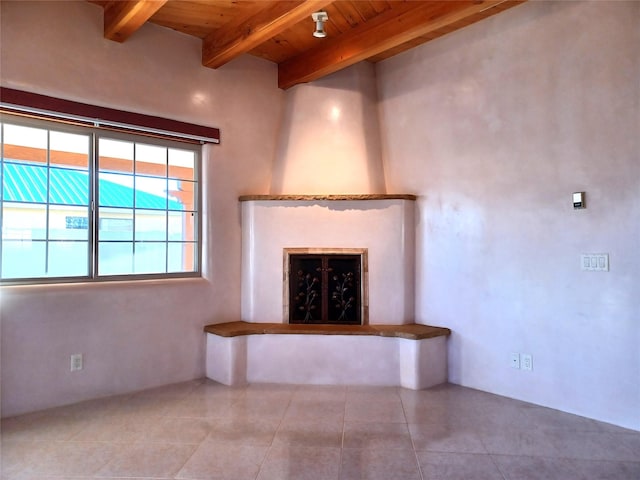 unfurnished living room with a large fireplace, beamed ceiling, wooden ceiling, and tile patterned flooring