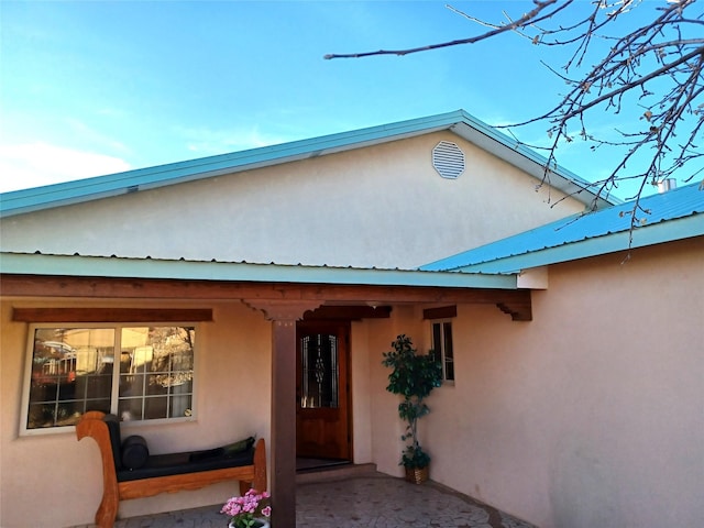 doorway to property featuring metal roof and stucco siding