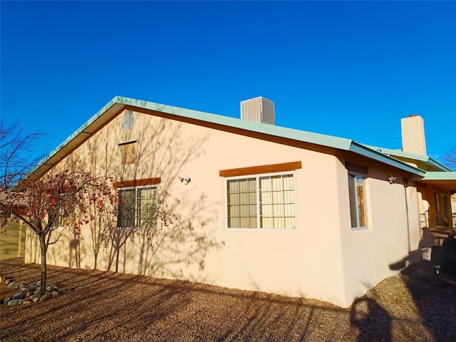 view of home's exterior with a chimney and stucco siding