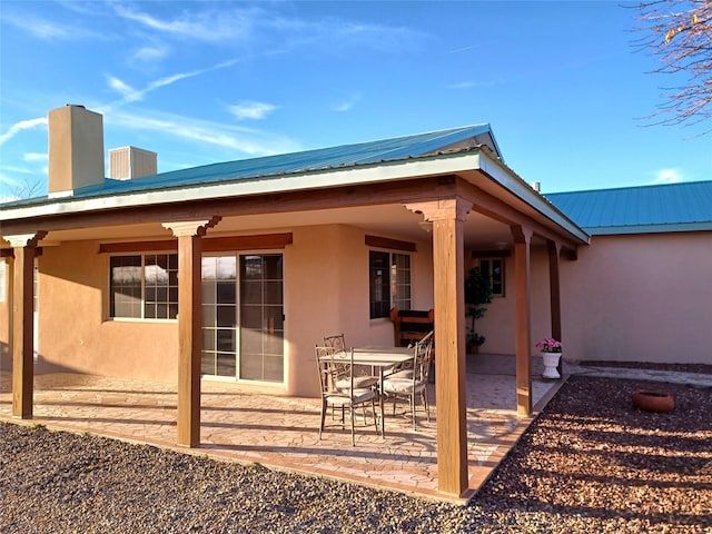 rear view of property featuring metal roof, a patio, and stucco siding