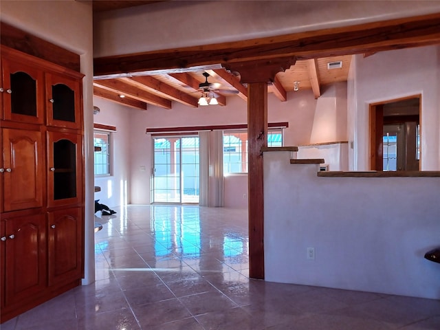 interior space with beamed ceiling, dark tile patterned flooring, and ceiling fan