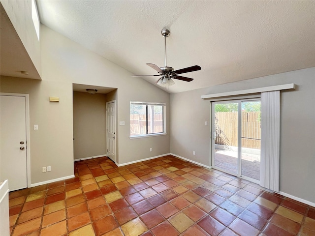 tiled empty room with ceiling fan, a healthy amount of sunlight, a textured ceiling, and high vaulted ceiling