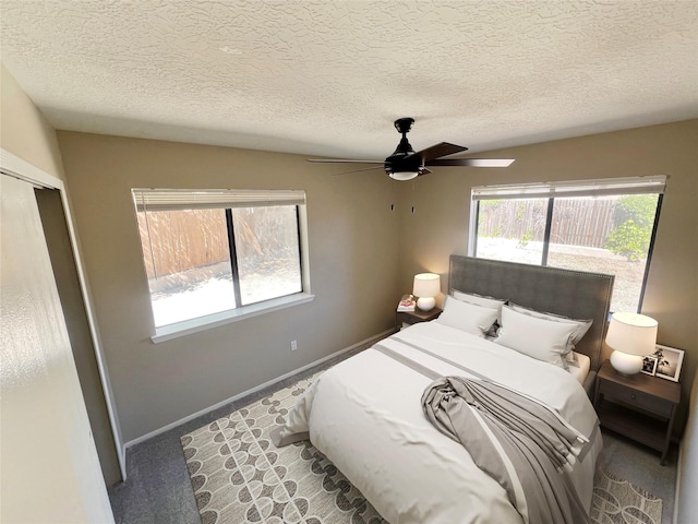 carpeted bedroom with ceiling fan and a textured ceiling