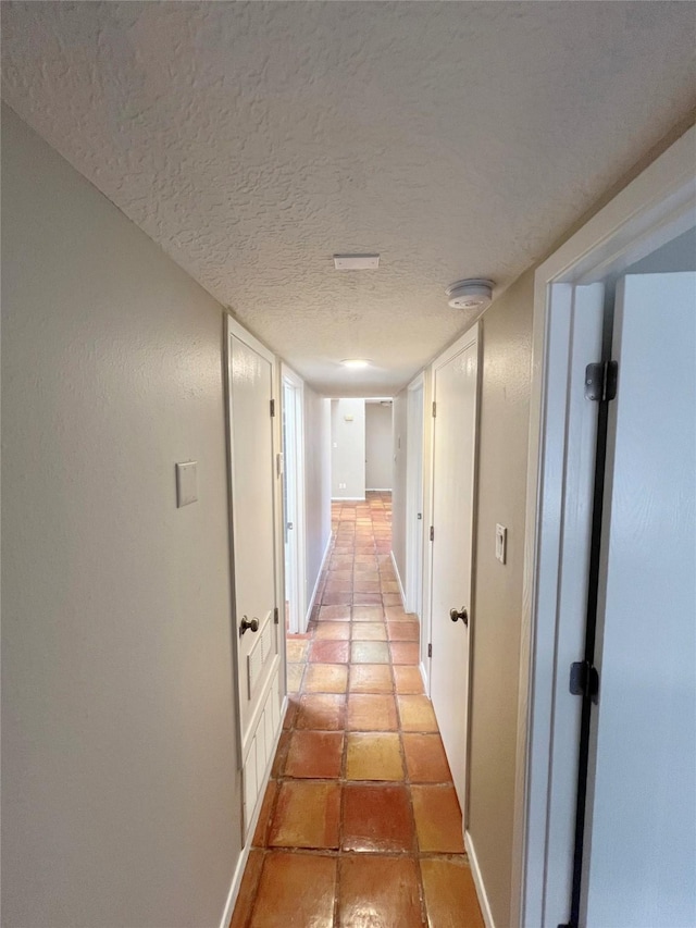 hall featuring light tile patterned floors and a textured ceiling