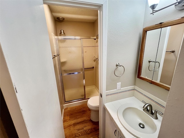 bathroom with vanity, toilet, a textured ceiling, walk in shower, and wood-type flooring