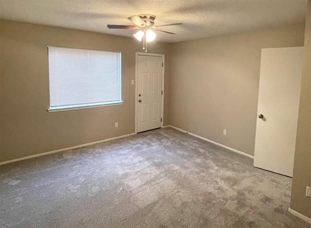 carpeted spare room featuring ceiling fan and a textured ceiling