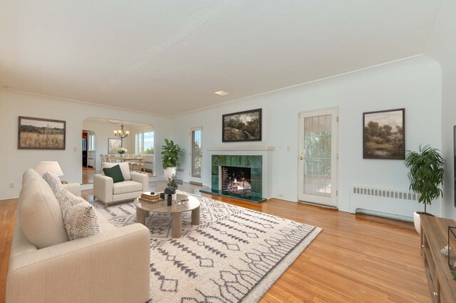 living room with hardwood / wood-style floors, radiator heating unit, a tile fireplace, and an inviting chandelier