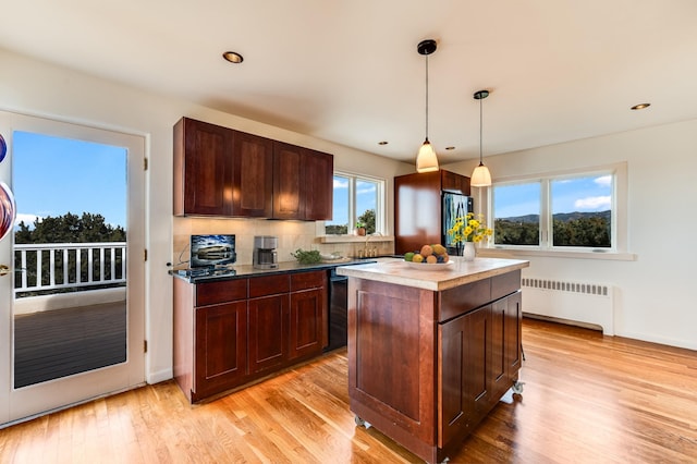 kitchen featuring pendant lighting, radiator, a center island, and a healthy amount of sunlight