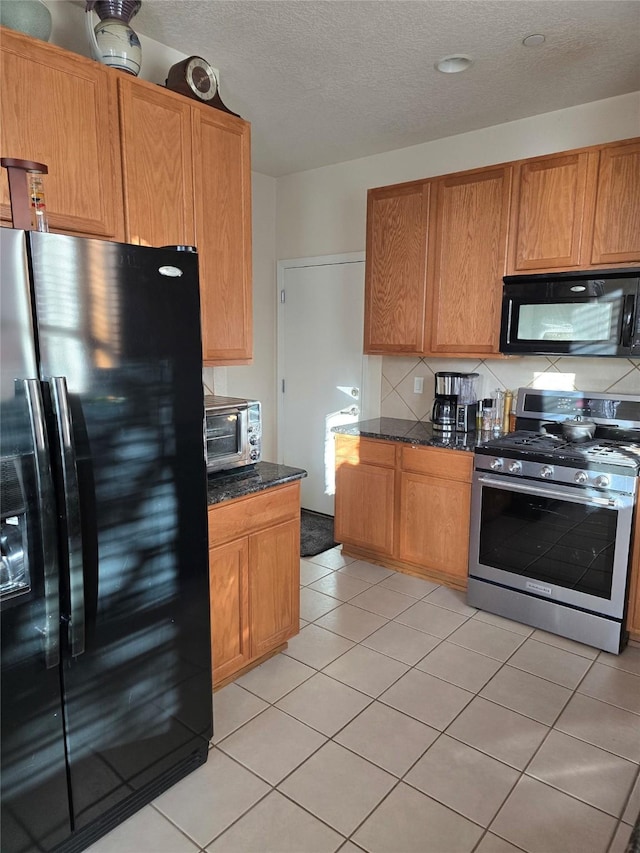 kitchen featuring black appliances, light tile patterned flooring, backsplash, and dark stone counters