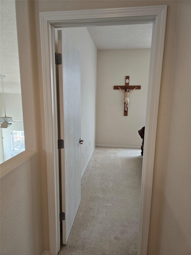 hall with light colored carpet and a textured ceiling