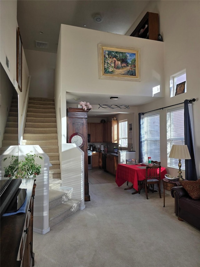 carpeted living room with a towering ceiling and sink