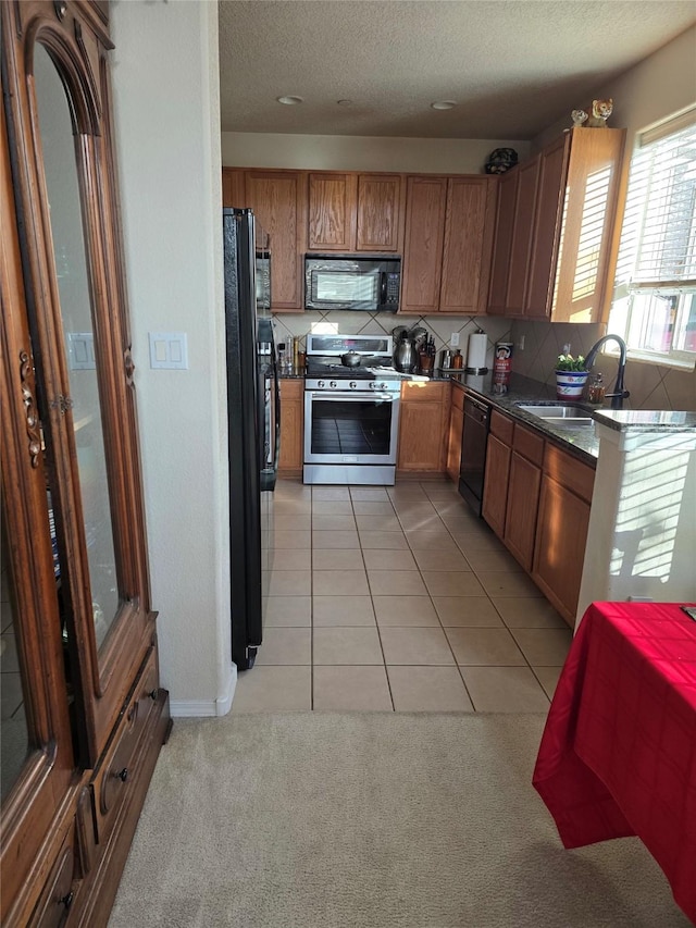 kitchen with sink, backsplash, a textured ceiling, light tile patterned floors, and black appliances