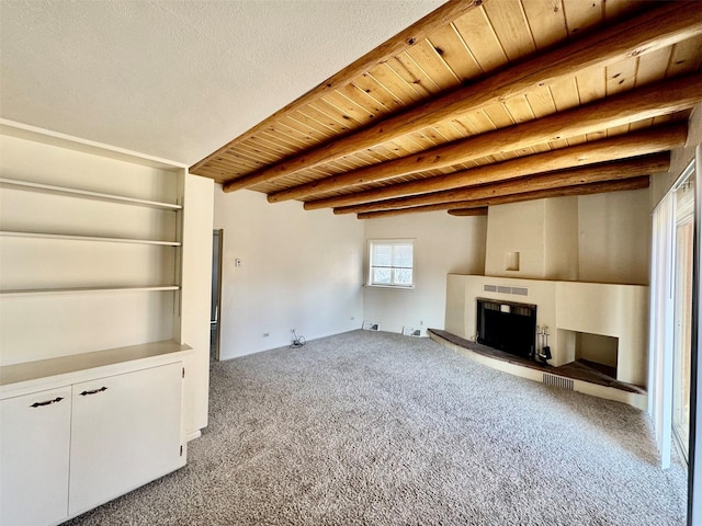 unfurnished living room featuring beam ceiling, light colored carpet, and wood ceiling