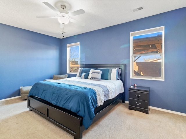 carpeted bedroom featuring ceiling fan and a textured ceiling