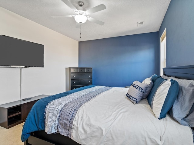 carpeted bedroom featuring ceiling fan and a textured ceiling