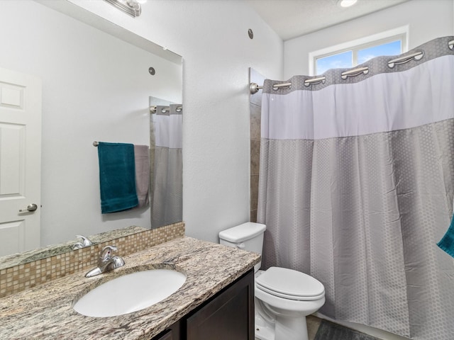 bathroom with curtained shower, vanity, and toilet