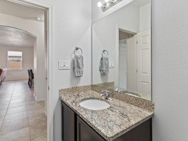 bathroom with tile patterned flooring, vanity, and a textured ceiling