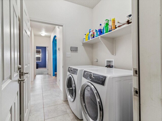 clothes washing area with washer and dryer and light tile patterned floors