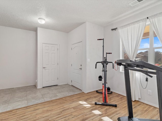 workout room with a textured ceiling and light hardwood / wood-style flooring