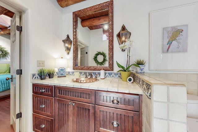 605 Abeyta St, Santa Fe, NM 87505 - bathroom with vanity, decorative backsplash, beamed ceiling, and toilet