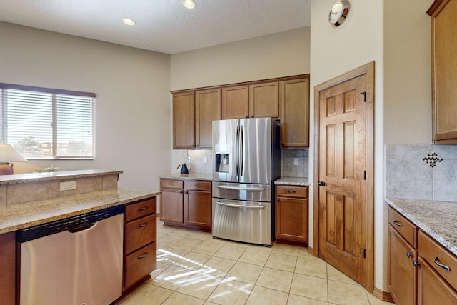 kitchen featuring light tile patterned floors, light stone countertops, appliances with stainless steel finishes, and tasteful backsplash