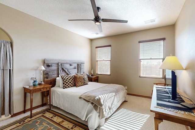 carpeted bedroom with a textured ceiling, ceiling fan, and multiple windows