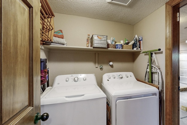 laundry room with a textured ceiling and washer and clothes dryer