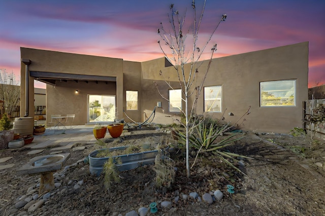 back house at dusk featuring a patio area