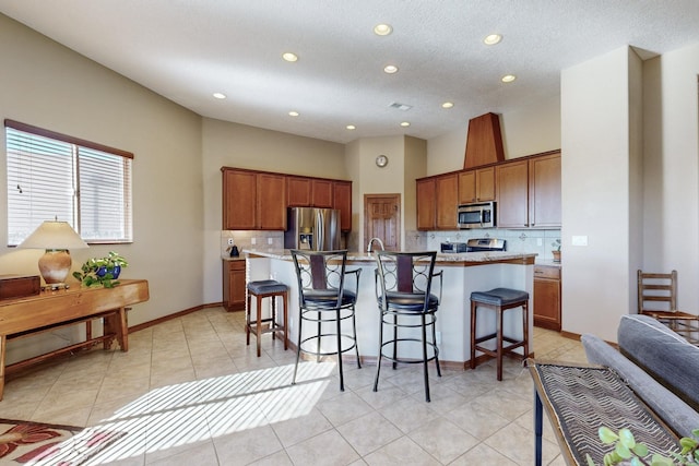 kitchen with backsplash, a breakfast bar, a kitchen island with sink, and appliances with stainless steel finishes