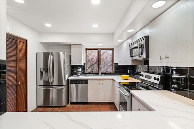 kitchen with backsplash, light stone counters, sink, and stainless steel appliances