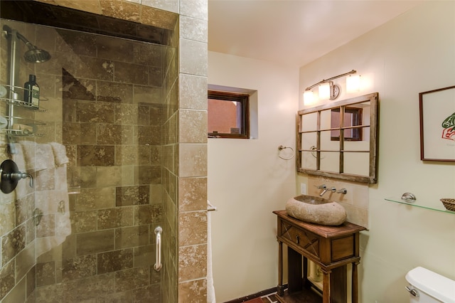 bathroom with tiled shower, vanity, and toilet