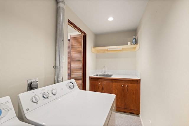 laundry room with cabinets, washer and clothes dryer, and sink