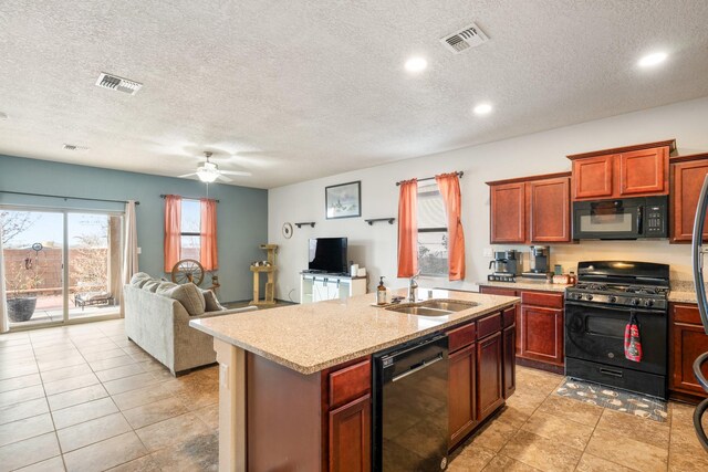 kitchen featuring sink, light stone countertops, black appliances, an island with sink, and a textured ceiling