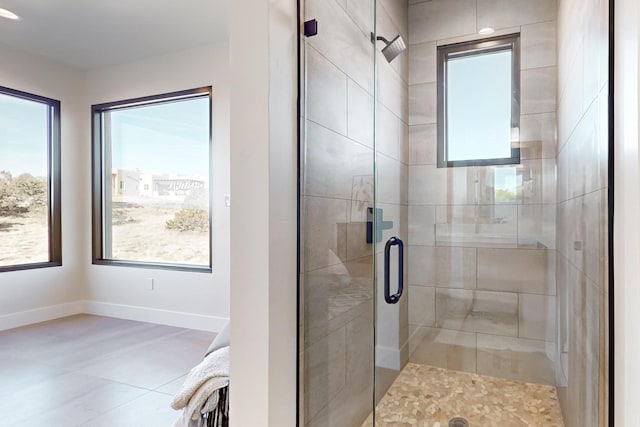 bathroom with plenty of natural light, a shower with shower door, and tile patterned flooring