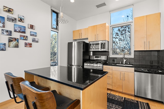 kitchen featuring sink, stainless steel appliances, light brown cabinetry, and tasteful backsplash