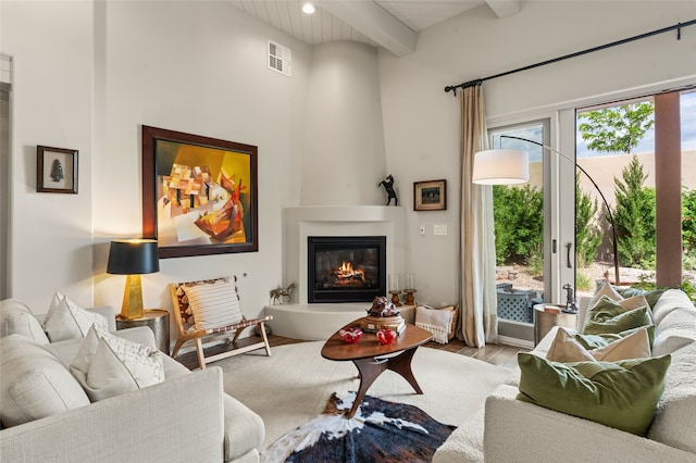 living room with a large fireplace, beamed ceiling, wood ceiling, and light hardwood / wood-style flooring