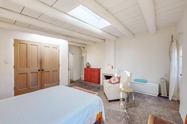 bedroom featuring a brick fireplace, beam ceiling, and a skylight