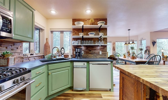 kitchen featuring wood counters, appliances with stainless steel finishes, sink, decorative light fixtures, and green cabinets