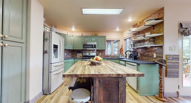 kitchen featuring sink, green cabinetry, light wood-type flooring, appliances with stainless steel finishes, and tasteful backsplash