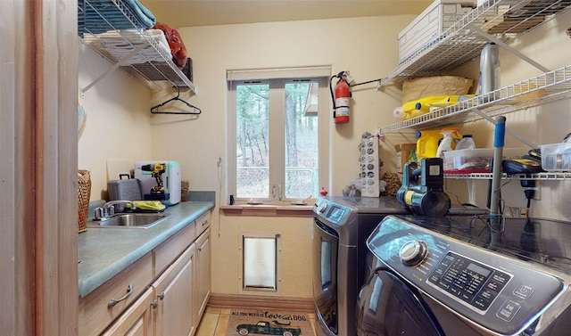 laundry room with sink, light tile patterned floors, cabinets, and independent washer and dryer