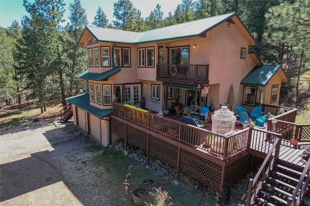 back of house with dirt driveway, metal roof, and stucco siding