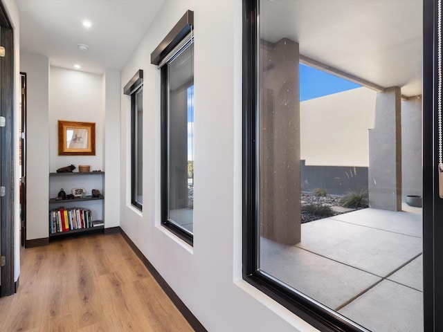 hall with a wealth of natural light and hardwood / wood-style floors